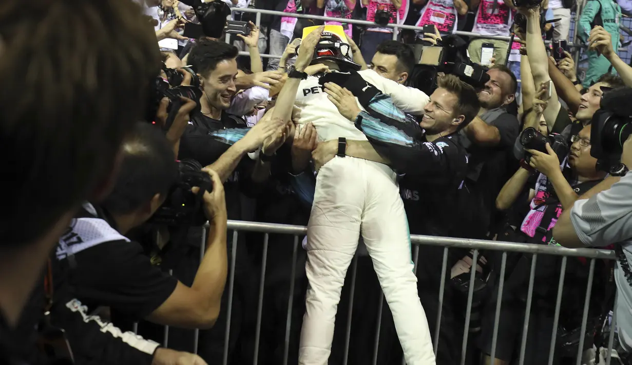 Pebalap Mercedes, Lewis Hamilton merayakan kemenangan bersama awak tim pada balapan F1 Singapura di Marina Bay City Circuit Singapore,(17/9/2017). (AP/Yong Teck Lim)