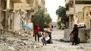 Sebuah keluarga melewati reruntuhan bangunan untuk kembali ke rumah mereka di kota modern Palmyra, berdekatan dengan kota kuno Suriah, Sabtu (9/4). Warga kembali ke rumah mereka setelah dibebaskannya dua kota tersebut dari tangan ISIS. (Louai BESHARA/AFP)