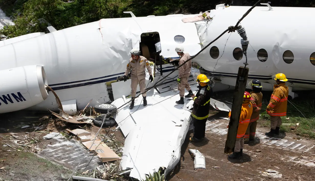 Petugas layanan darurat berada di lokasi pesawat jet pribadi Gulfstream G200 yang tergelincir di Bandara Tegucigalpa, Honduras, Selasa (22/5). Bandara Tegucigalpa telah lama dikenal sebagai salah satu bandara berbahaya. (AP/Fernando Antonio)