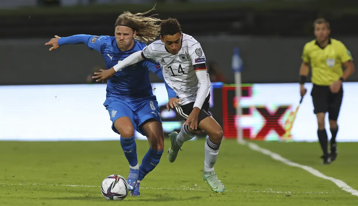 Gelandang Jerman, Jamal Musiala berusaha melewati pemain Islandia, Birkir Bjarnason dalam lanjutan laga kualifikasi grup J Piala Dunia 2022 di Reykjavik, Islandia, Kamis (9/9/2021). Jerman menang telak atas Islandia dengan skor 4-0. (AP Photo/Arni Torfason)