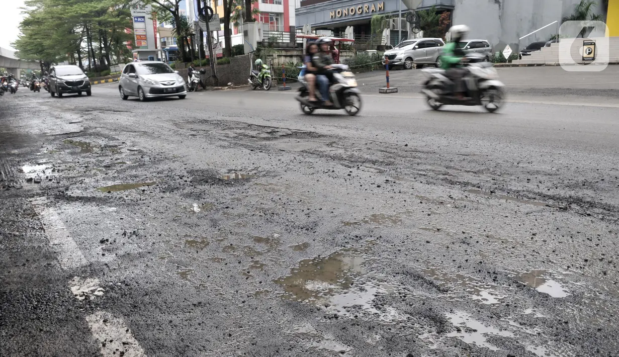 Kendaraan melintas dekat jalan berlubang di kawasan Kelapa Gading, Jakarta, Minggu (1/3/2020). Kepala Dinas Bina Marga DKI Jakarta Hari Nugroho mengatakan banjir pada Februari 2020 merusak 495 jalan Ibu Kota dengan 3.290 titik lubang yang tersebar di lima wilayah. (merdeka.com/Iqbal Nugroho)
