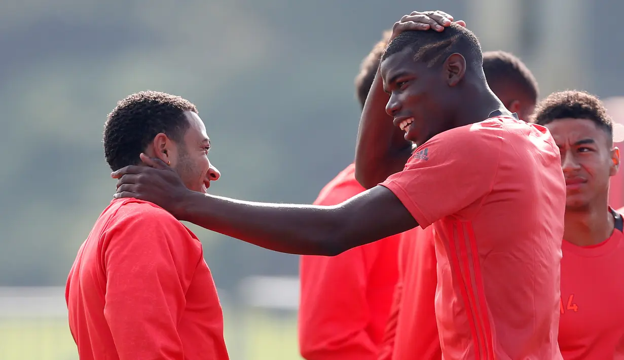 Gelandang MU, Paul Pogba berbincang dengan penyerang Memphis Depay saat mengikuti latihan di Manchester United Training Ground, Inggris, (14/9). MU akan bertanding pada laga perdana di Liga Europa melawan tim asal Belanda Feyenoord. (Reuters/Ed Sykes)