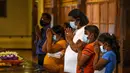 Para bakta Buddhis mengenakan masker berdoa di tengah kekhawatiran akan penyebaran coronavirus novel COVID-19 di Kuil Peninggalan Gigi Suci di Kandy (18/3/2020). (AFP/Ishara S. Kodikara)