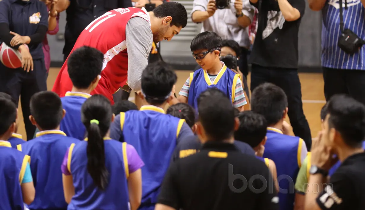  Enes Kanter memberikan gelang NBA kepada seorang peserta di Britama Arena, Jakarta, Kamis (18/5/2017). Coaching clinic singkat dari Enes Kanter penuh keceriahan. (Bola.com/Nicklas Hanoatubun)