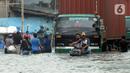 Pengendara sepeda motor mendorong kendaraannya melewati banjir rob di kawasan Pelabuhan Sunda Kelapa, Jakarta, Selasa (7/12/2021). Banjir rob setinggi satu meter memutus Jalan Kerapu yang menghubungkan Ancol-Pluit. (merdeka.com/Arie Basuki)