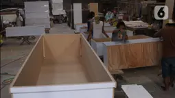 Pekerja menyelesaikan pembuatan peti jenazah COVID-19 di Batu Ceper, Kota Tangerang, Banten, Selasa (29/6/2021). Produksi peti jenazah COVID-19 di tempat tersebut meningkat hingga dua kali lipat dari 500 buah menjadi 1.000 buah per minggunya akibat tingginya permintaan. (Liputan6.com/Angga Yuniar)