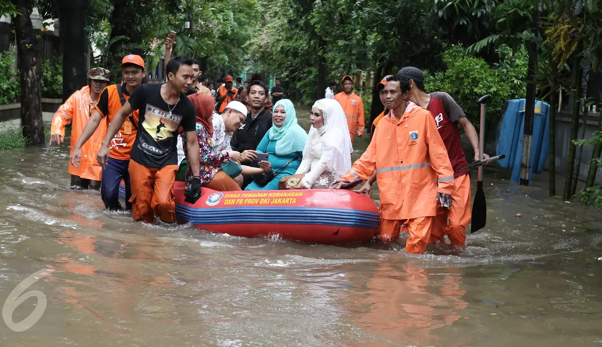 Keluarga pengantin Maya di evakuasi pasukan orange usai melakukan akad nikah di KUA Mampang Prapatan, Jakarta, Selasa (21/2). Walaupun banjir sepasang pengantin ini tetap melakukan akad nikah. (Liputan6.com/Herman Zakharia)