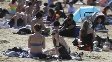 Orang-orang menikmati cuaca hangat di Ruislip Lido di London, Selasa (30/3/2021).  Suhu di beberapa bagian Inggris diperkirakan akan lebih hangat secara signifikan minggu ini karena keluarga dan teman berkumpul kembali dan kegiatan olahraga luar ruangan diizinkan untuk dilanjutkan di Inggris. (AP Ph