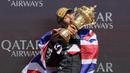 Pembalap Mercedes, Lewis Hamilton mencium piala saat merayakan kemenangannya di Formula 1 GP Inggris 2024 yang berlangsung di Sirkuit Silverstone, Inggris, Minggu (08/07/2024). (AFP/Benjamin Cremel)