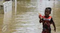 Seorang anak bermain di tengah jalan permukiman Bukit Duri, Jakarta yang terendam banjir, Kamis (16/2). Meluapnya Bendungan Katulampa, Bogor, menyebabkan permukiman kawasan Bukit Duri tergenang air dengan ketinggian 10 - 80 cm. (Liputan6.com/Helmi Afandi)