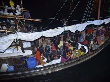 Pengungsi Rohingya duduk di perahu saat tiba di Pelabuhan Krueng Geukueh di Aceh Utara, Jumat pagi (31/12/2021). Sedikitnya 120 orang etnis Rohingya yang sempat terombang-ambing di lautan selama beberapa hari akhirnya dievakuasi ke daratan Aceh. (AP Photo/Rahmat Mirza)