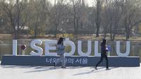 Pengunjung mengenakan masker untuk membantu mengekang penyebaran virus corona berjalan di dekat pajangan logo ibu kota Korea Selatan, Seoul, Rabu (8/12/2021). Untuk pertama kalinya, Korea Selatan (Korsel) melaporkan lebih dari 7.000 kasus Corona dalam 24 jam terakhir. (AP Photo/Lee Jin-man)