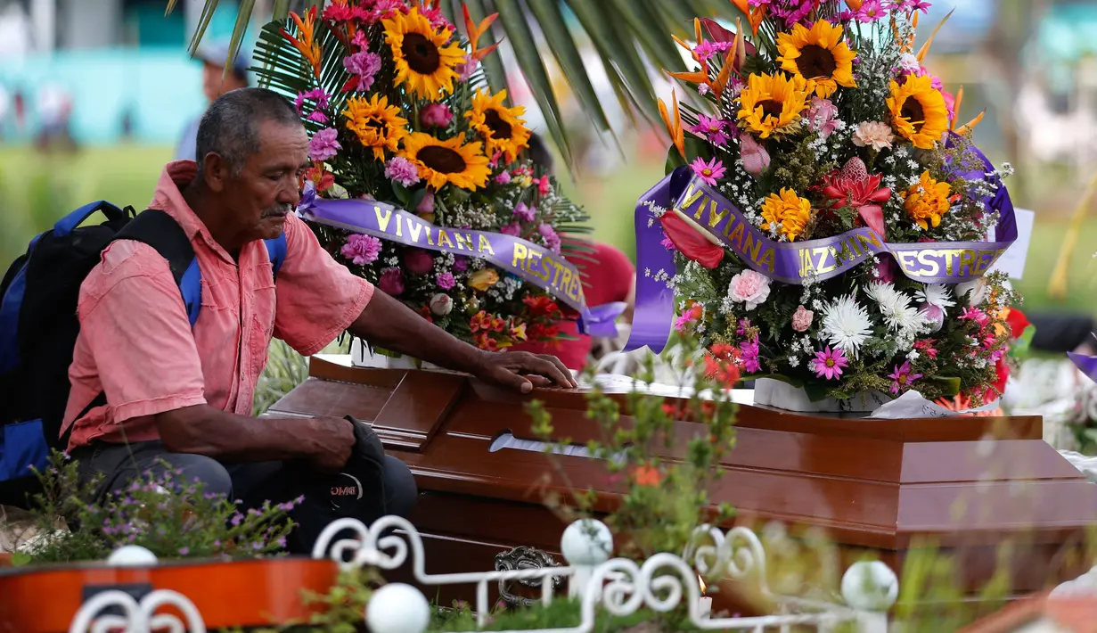 Seorang pria berdoa disamping peti jenazah korban tanah longsor di Mocoa, Kolombia, (3/4). Bencana tanah longsor tersebut disebabkan hujan deras yang terus mengguyur sejumlah kawasan di Kolombia. (AP Photo / Fernando Vergara)