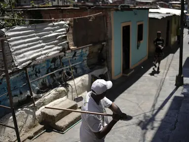 Seorang pria melempar tutup botol ke pemukul saat memainkan permainan tradisional "chapitas" atau Caps, di Caracas, Venezuela, 29 Januari 2022. Permainan populer mirip dengan bisbol ini dimainkan dengan tutup botol sebagai pengganti bola, dan tongkat sebagai pengganti pemukul. (AP/Matias Delacroix)