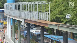 Suasana pembangunan jembatan penyeberangan orang (JPO) di Halte Kuningan Timur, Jakarta, Selasa (9/1). Pembangunan tersebut untuk menggantikan JPO yang dibongkar karena pembangunan proyek LRT. (Liputan6.com/Immanuel Antonius)