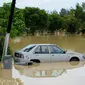 Sebuah mobil terlihat sebagian terendam banjir di daerah pemukiman, Batu Berendam, Malaka, Malaysia, 3 Januari 2022. Setidaknya ada 50 orang tewas dalam banjir di Malaysia. (NAZRULHAD HASHIM/AFP)