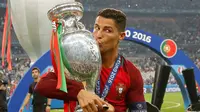 Cristiano Ronaldo menciumi Piala Eropa 2016 usai memenangkan laga melawan Prancis di Stade de France, Senin (11/7). Portugal menang dengan skor tipis 1-0. (REUTERS)
