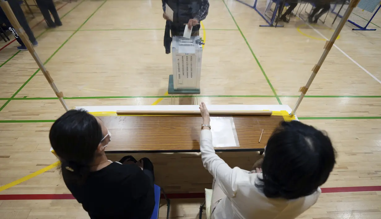 Perwakilan dari komisi administrasi pemilihan lokal menyaksikan para pemilih memberikan suara mereka untuk pemilihan majelis rendah di sebuah TPS, Tokyo, Jepang, Minggu (31/10/2021). Jepang menggelar Pemilu di tengah pandemi COVID-19. (AP Photo/Eugene Hoshiko)