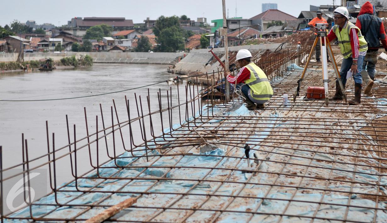 Pekerja memasang rangka untuk pengerjaan jalan di lokasi normalisasi sungai Ciliwung, Jakarta, Selasa (27/2). Proses normalisasi Sungai Ciliwung kembali dilanjutkan setelah terhenti karena meningginya air. (Liputan6.com/Yoppy Renato)