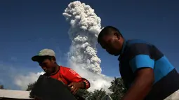 Warga beraktivitas di tengah erupsi Gunung Sinabung yang kembali memuntahkan asap dan abu vukanik ke udara di Karo, Sumatera Utara, (18/1). Aktivitas Gunung Sinabung terus mengalami peningkatan. (AFP Photo/YT Haryono)