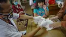 Seorang anak mengamati saat kucingnya disuntik vaksin rabies di kantor kelurahan Petukangan Selatan, Jakarta, Rabu (15/9/2021). Dinas Ketahanan Pangan dan Pertanian memberikan vaksinasi rabies bagi hewan peliharaan milik warga untuk mengantisipasi penyakit rabies. (Liputan6.com/Faizal Fanani)