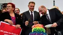 Pemimpin kelompok parlementer partai SPD, Thomas Oppermann (tengah) bersama Martin Schulz memotong kue pengantin dengan warna pelangi dan dihiasi patung-patung dua wanita dan dua pria di Bundestag di Berlin (30/6). (AFP Photo/Tobias Schwarz)