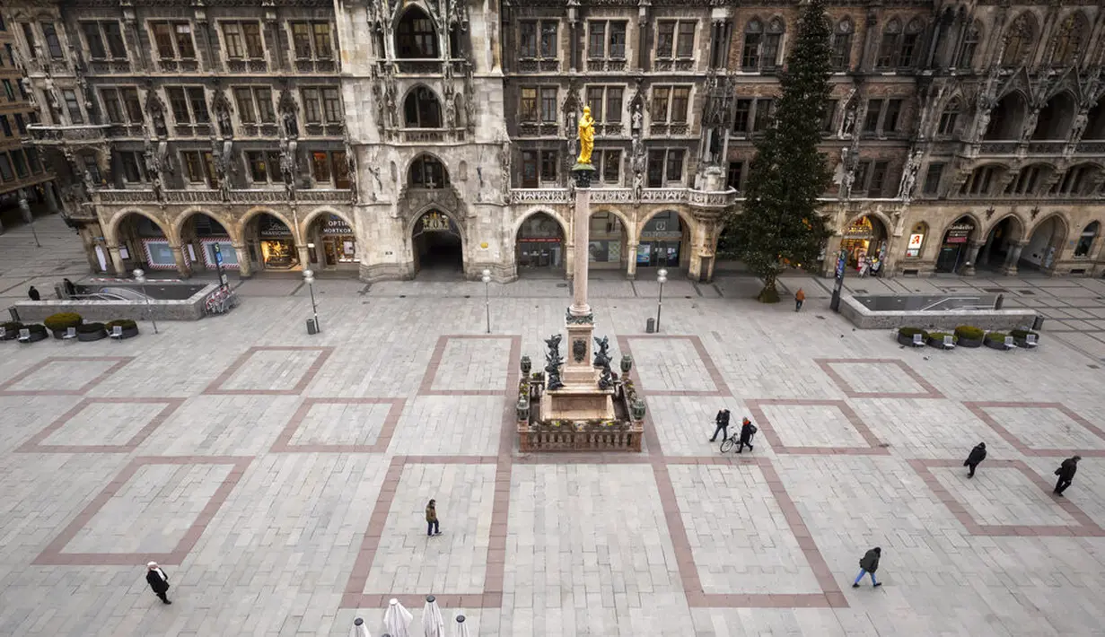 Beberapa orang berjalan melintasi Marienplatz yang hampir kosong selama lockdown di Kota Munich, Jerman, Selasa (5/1/2021). Pemerintah Jerman sepakat untuk memperpanjang langkah-langkah lockdown hingga 31 Januari untuk mengekang penyebaran COVID-19. (Peter Kneffel/dpa via AP)