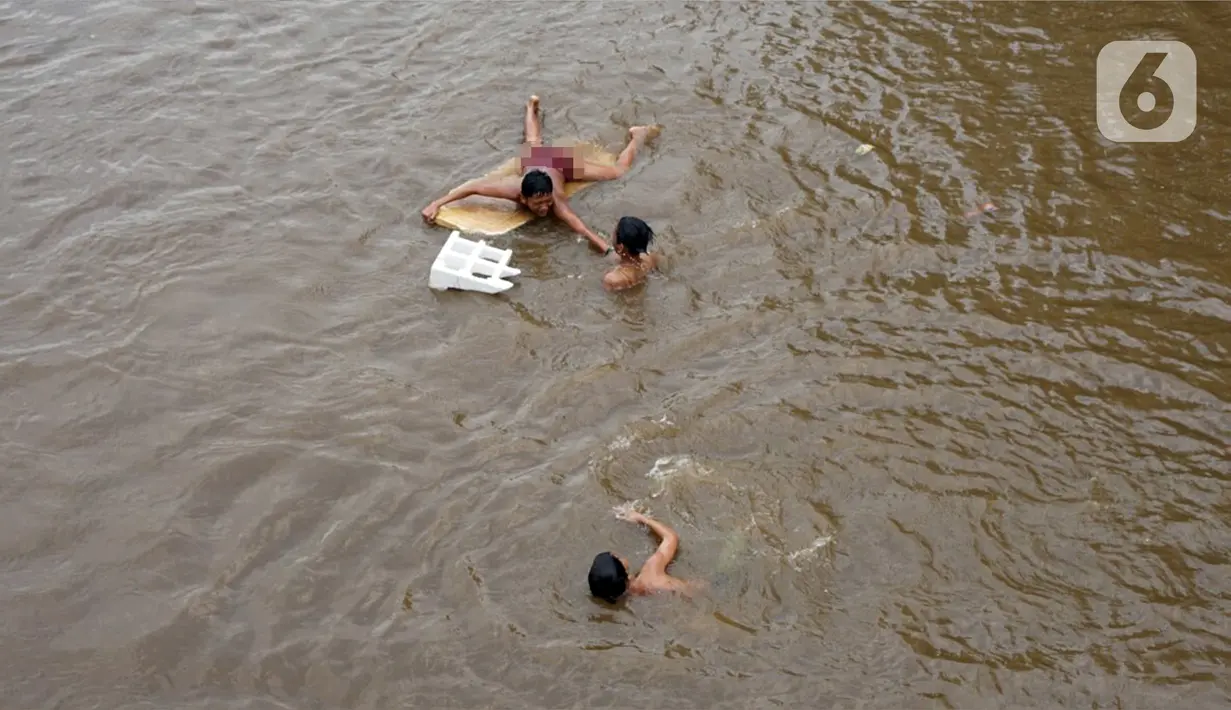 Anak-anak berenang di aliran Sungai Ciliwung, Jatinegara, Jakarta Timur, Sabtu (4/7/2020). Minimnya lahan bermain menyebabkan anak-anak tersebut bermain tidak pada tempatnya, meski dapat membahayakan keselamatan. (Liputan6.com/Immanuel Antonius)