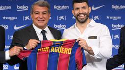 Penyerang Sergio Aguero (kanan) berpose dengan presiden Joan Laporta selama presentasi resminya sebagai pemain baru Barcelona di stadion Camp Nou, Spanyol (31/65/2021).  Barcelona dan Sergio Aguero sama-sama sepakat untuk menyelipkan klausul pelepasan dalam kontraknya. (AFP Photo/Lluis Gene)