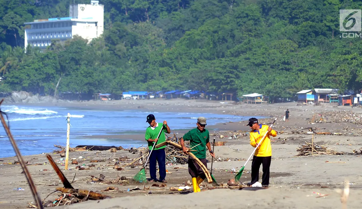 Sukarelawan yang berasal dari warga lokal membersihkan sampah yang berserakan akibat terbawa ombak pasang di kawasan Pantai Citepus, Pelabuhan Ratu, Sukabumi, Jumat (4/1). (Merdeka.com/Arie Basuki)