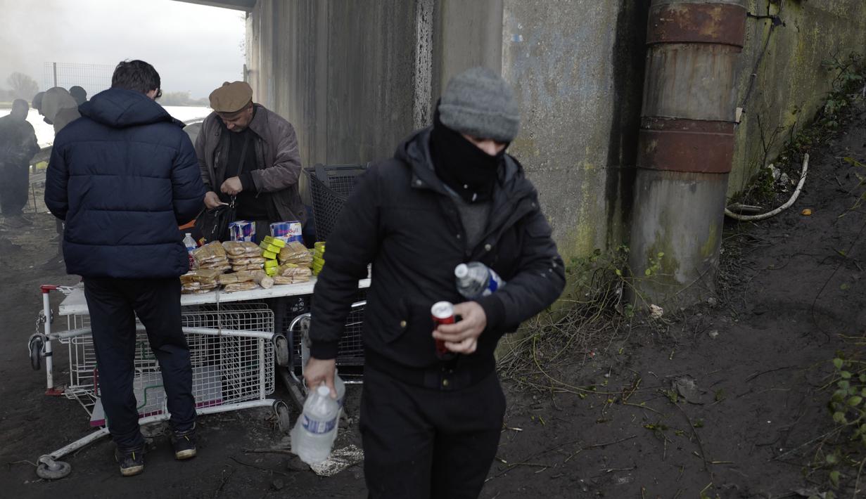 Seorang migran membeli barang di kamp darurat di Calais, Prancis utara, Sabtu (277/11/2021). Di kamp-kamp darurat di luar Calais, para migran yang putus asa menunggu kesempatan untuk mencoba menyeberangi Selat Inggris. (AP Photo/Rafael Yaghobzadeh)