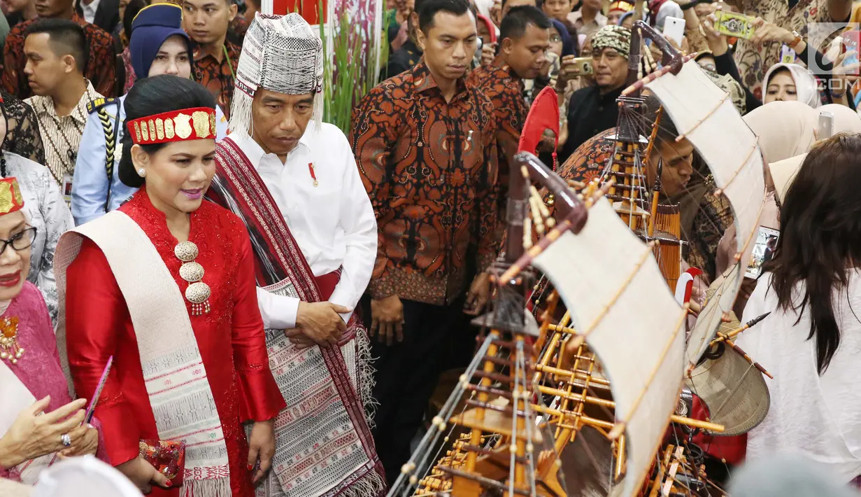 Presiden Jokowi didampingi Ibu Negara, Iriana melihat produk kerajinan pada Pameran Kriyanusa Dewan Kerajinan Nasional 2017 di Jakarta Convention Center, Rabu (27/9). Keduanya tampak serasi berpakaian adat Batak Toba Samosir. (Liputan6.com/Angga Yuniar)
