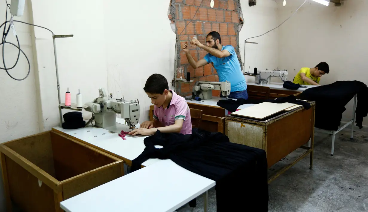 Bocah pengungsi Suriah, Muhamed (kiri) dan kakaknya (kanan) bekerja di sebuah pabrik tekstil, Istanbul, Turki, (24/6). Meski seumurannya masih menikmati bangku sekolah, mereka menikmati pekerjaan mereka. (REUTERS/Murad Sezer)