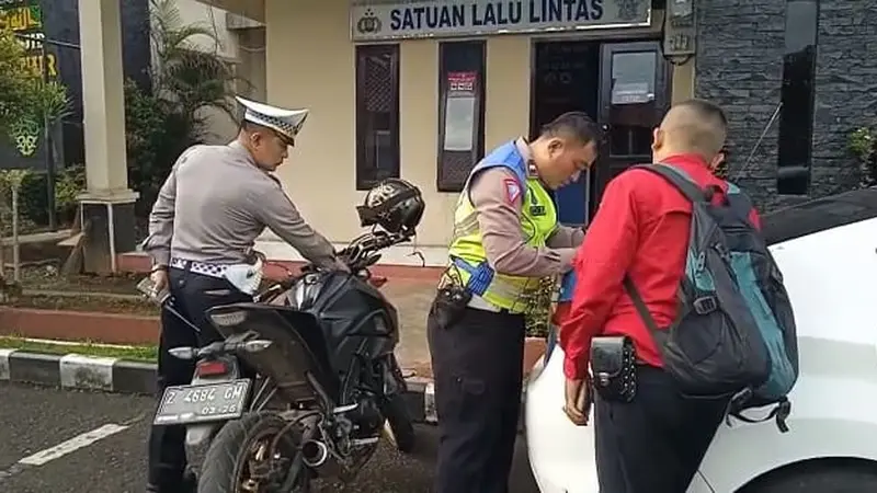 Dua petugas Satlantas Polres Tasikmalaya tengah melakukan penertiban knalpot brong atau bising yang berpotensi mengganggu kenyamanan warga saar Ramadan. (Liputan6.com/Jayadi Supriadin)
