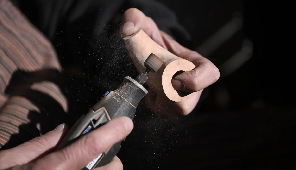 Marco Bacigalupi membuat pipa rokok tradisional dari kayu di Gavi, Italia (14/11). Pengrajin Bacigalupi memulai membuat pipa rokok dari kayu ini sejak tahun 80-an. (AFP Photo/Marco Bertorello)