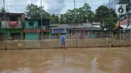 Warga berjalan melewati lumpur sisa banjir di Kelurahan Rawa Jati, Jakarta, Selasa (9/2/2021). Endapan lumpur yang mengendap akibat luapan Kali Ciliwung. (merdeka.com/Imam Buhori)
