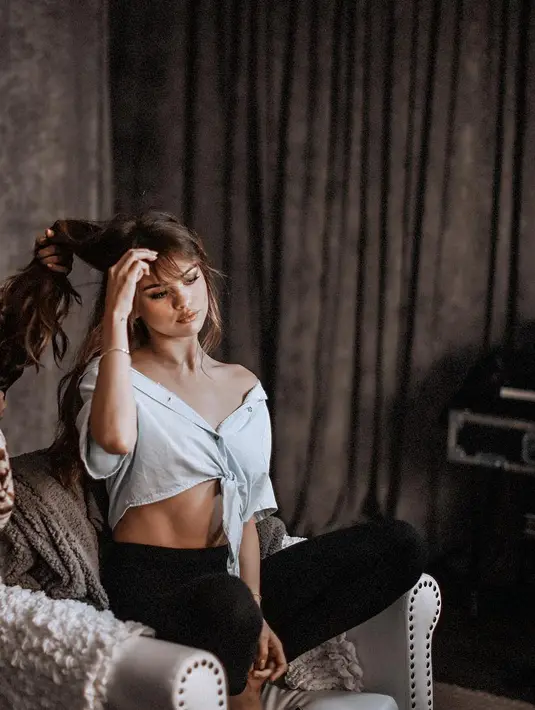 Melalui akun instagramnya @selenagomez, nampak Selena Gomez sedang berjongkok di atas sofa sambil membenahi rambut coklat tebalnya. (instagram/Bintang.com)