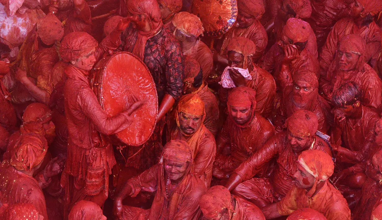 Sejumlah pria yang tubuhnya berlumuran bubuk merah beristirahat saat mengikuti perayaan Lathmar Holi di Barsana, Uttar Pradesh, India (6/3). Ribuan berkumpul untuk menyaksikan perayaan Lathmar Holi. (AFP Photo/STR)