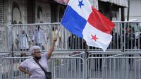 Seorang wanita memegang bendera Panama saat anggota serikat guru yang mogok memprotes selama pawai menuju Majelis Nasional di Panama City, Senin (11/7/2022). Masker tidak lagi diperlukan kecuali di rumah sakit dan transportasi umum. (AP Photo/Arnulfo Franco)