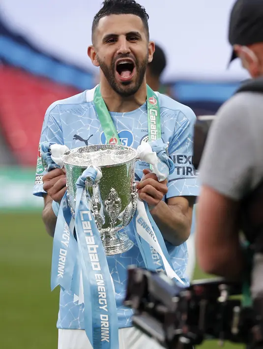 Gelandang Manchester City, Riyad Mahrez berpose dengan trofi saat merayakan kemenangan atas Tottenham Hotspur pada pertandingan final Piala Liga Inggris di stadion Wembley di London, Senin (26/4/2021). (AP Photo/Alastair Grant)