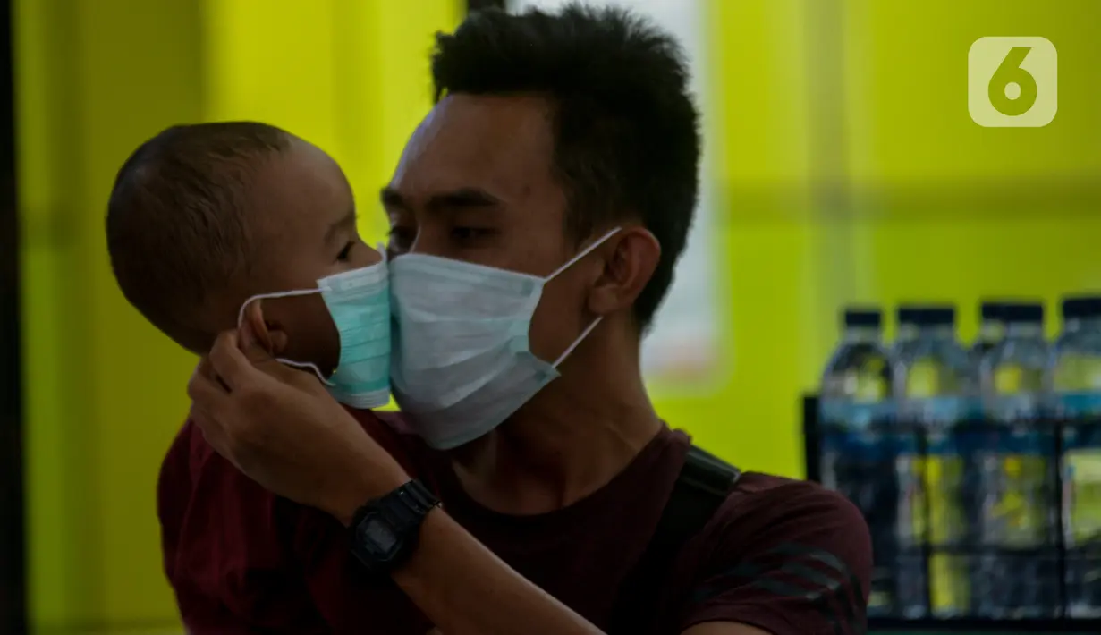 Calon penumpang kereta api mengenakan masker saat berada di Stasiun Gambir, Jakarta Pusat, Jumat (31/01). Dalam rangka pencegahan Virus Corona, PT Kereta Api Indonesia (persero) melakukan sosialisasi kepada penumpang dengan membagi-bagikan masker di stasiun Gambir. (merdeka.com/Imam Buhori)