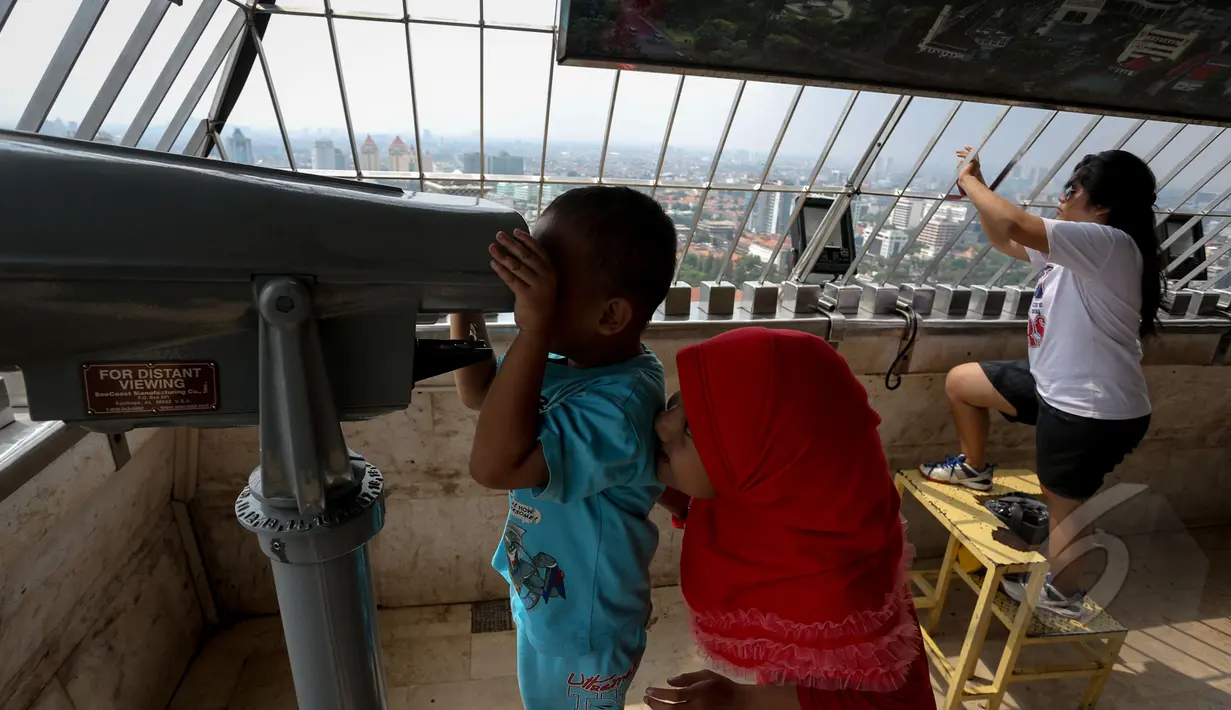 Dua orang bocah tampak menggunakan teropong untuk melihat Jakarta dari puncak Monas, Jakarta, Kamis (14/5/2015). Jumlah pengunjung mengalami peningkatan tinggi bertepatan libur kenaikan Isa Almasih. (Liputan6.com/Faizal Fanani)