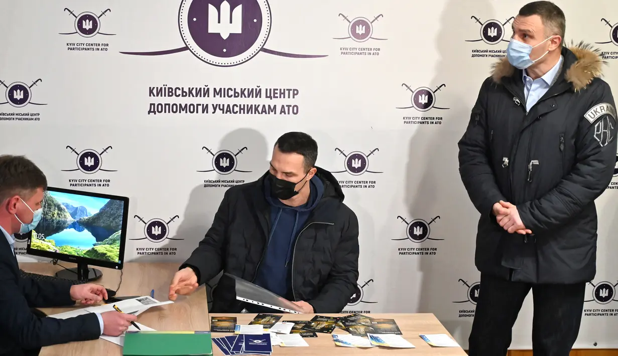 Wali Kota Kyiv Vitali Klitschko melihat saudaranya yang mantan petinju Ukraina Wladimir Klitschko mendaftar sebagai tentara cadangan di pusat perekrutan relawan, 2 Februari 2022. Wladimir beralasan cinta tanah air sehingga memaksanya untuk mempertahankan kemerdekaan Ukraina. (Genya SAVILOV/AFP)