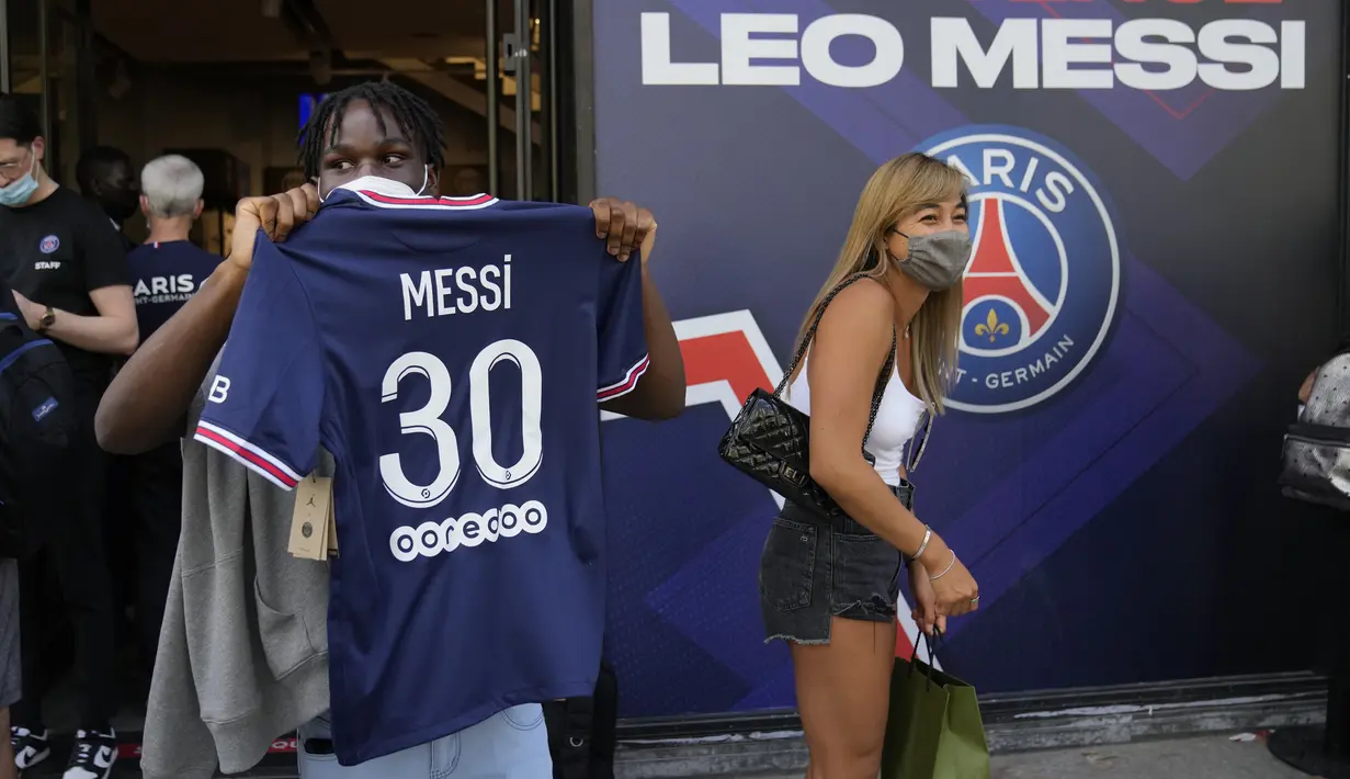 Seorang pendukung Paris Saint-Germain menunjukkan jersey bertuliskan nama Lionel Messi yang baru saja dibelinya di luar toko resmi PSG di Paris, Rabu (11/8/2021). Penjualan jersey PSG dengan nama Messi dan nomor punggung 30 laris manis, bahkan fans rela antre panjang. (AP Photo/Francois Mori)