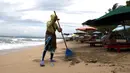 Seorang wanita menyapu sampah di Pantai Kuta, Bali, Jumat (4/2/2022). Bali kembali dibuka untuk pelancong asing dari semua negara setelah penerbangan internasional dilanjutkan untuk pertama kalinya dalam dua tahun, tapi pengunjung tetap wajib karantina. (AP Photo/Firdia Lisnawati)