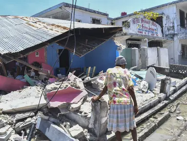 Seorang perempuan berdiri di depan rumah yang hancur setelah gempa bumi di Les Cayes, Haiti, Sabtu (14/8/2021). Wilayah Negara Haiti diguncang gempa berkekuatan magnitudo 7,1 pada Sabtu, 14 Agustus 2021 pukul 08.29.10 waktu setempat yang menewaskan lebih dari 300 jiwa. (AP Photo/Duples Plymouth)