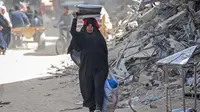 Seorang wanita Palestina membawa barang-barangnya di Khan Yunis di Jalur Gaza selatan pada 6 Maret 2024. Badan Bantuan dan Pekerjaan PBB (UNRWA) menyatakan bahwa rata-rata 63 perempuan terbunuh di Gaza setiap harinya, dan sekitar 37 diantaranya adalah ibu. (Foto: AFP)