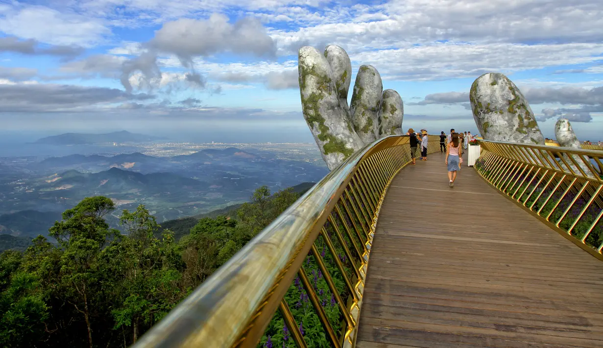 Pengunjung berjalan di sepanjang Golden Bridge di Perbukitan Ba Na dekat Danang, Vietnam, Selasa (31/7). Golden Bridge telah menarik banyak wisatawan sejak dibuka pada Juni 2018. (Linh PHAM/AFP)
