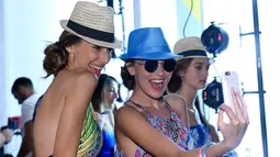 Dua model berselfie bersama usai didandani di belakang panggung jelang tampil dalam Peragaan Busana Renang, Art Hearts Fashion Miami Swim Week di Collins Park, Miami, Florida, (14/7). (Arun Nevader/Getty Images Seni Hati Mode/AFP)