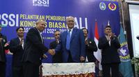 Ketum Asprov PSSI Bali I Ketut Suardana saat berjabat tangan dengan Anggota Exco PSSI Haruna Soemitro saat pelantikan pengurus di PSSI Bali di Denpasar beberapa waktu lalu. (Bola.com/Maheswara Putra)